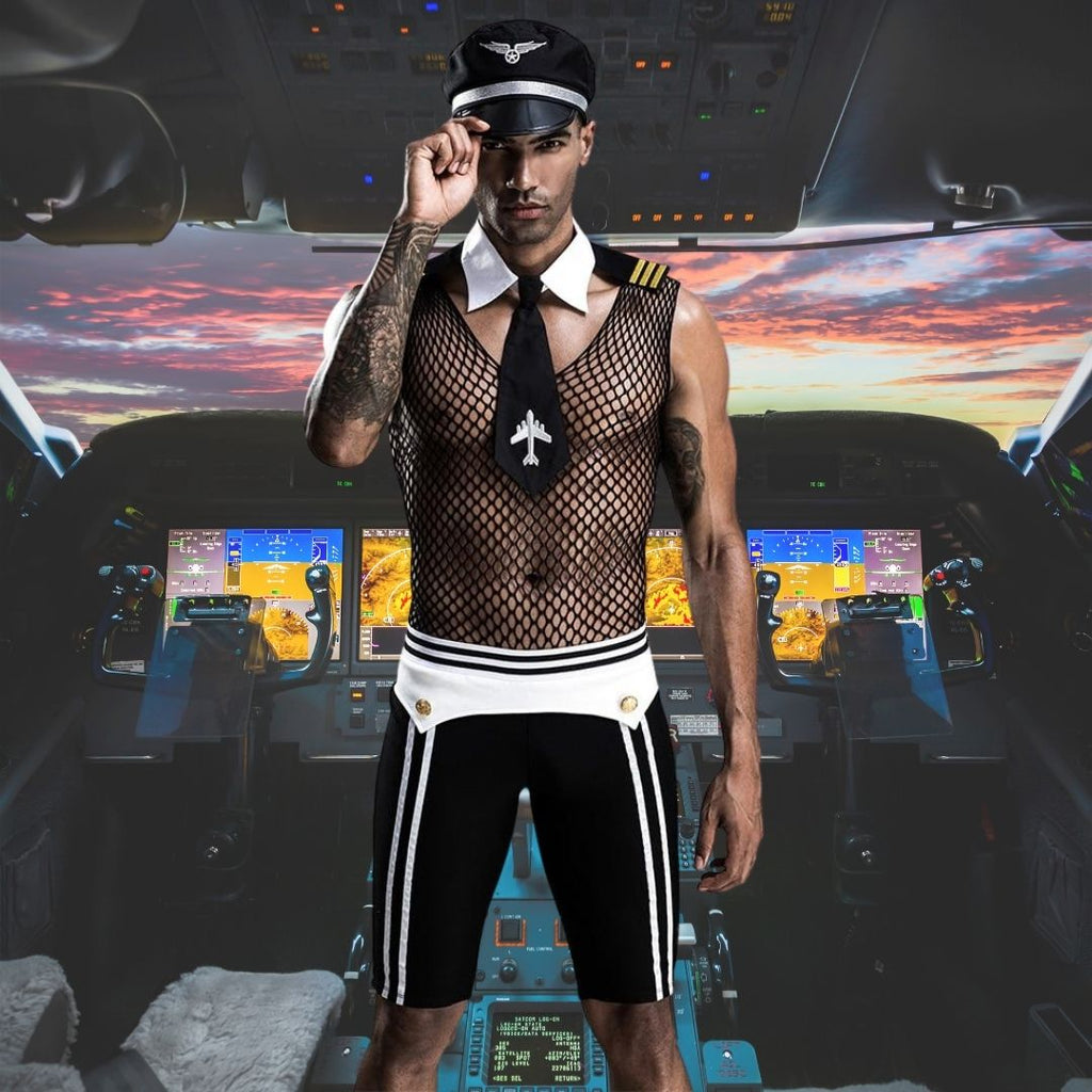 Man wearing a black mesh pilot costume with captain’s hat, tie, and striped shorts in a cockpit