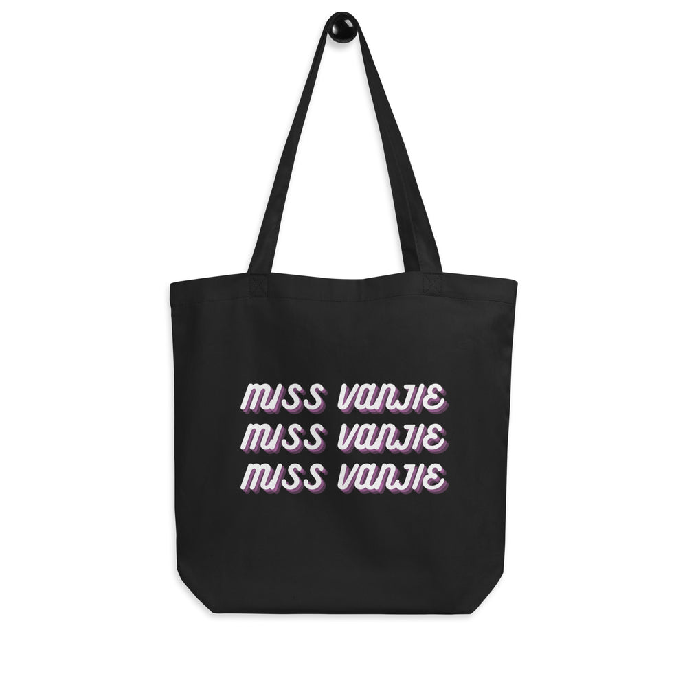 Front-facing black tote bag with three lines reading “MISS VANJIE” in white and purple