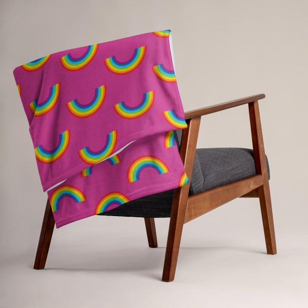 Rainbow-print throw blanket draped over a wooden armchair