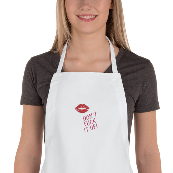 White embroidered apron with red lips and “DON’T FUCK IT UP!” slogan, worn by a model