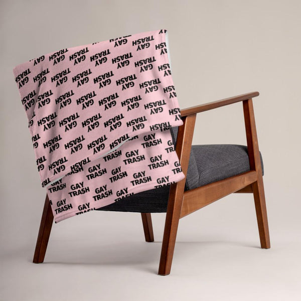 Pink Gay Trash throw blanket draped over a wooden armchair
