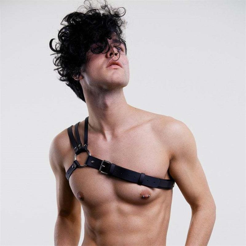 Close-up of a model wearing a black multi-strap chest harness with buckles and O-rings