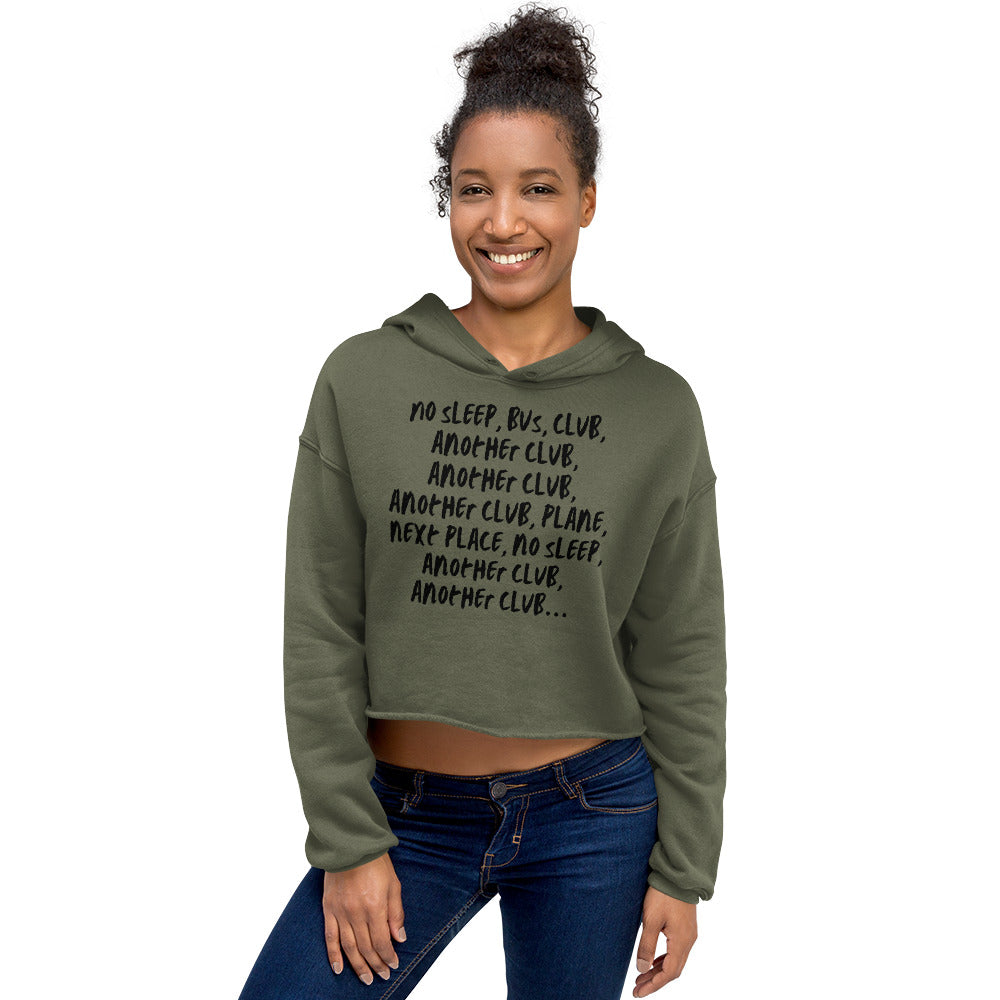 Model wearing an olive-green cropped hoodie with bold black multi-line text on the front