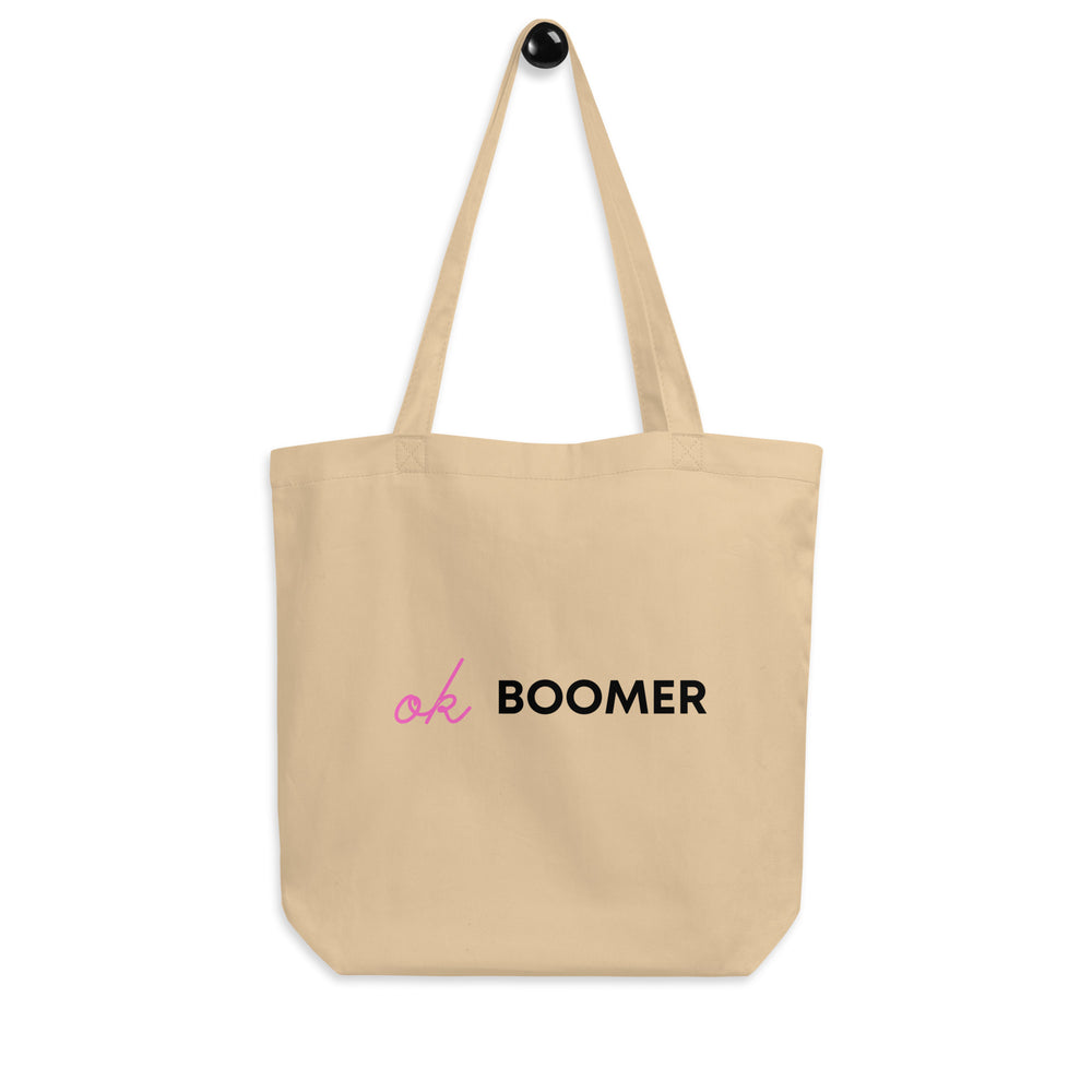 Front view of a beige tote bag reading “Ok BOOMER” in pink and black