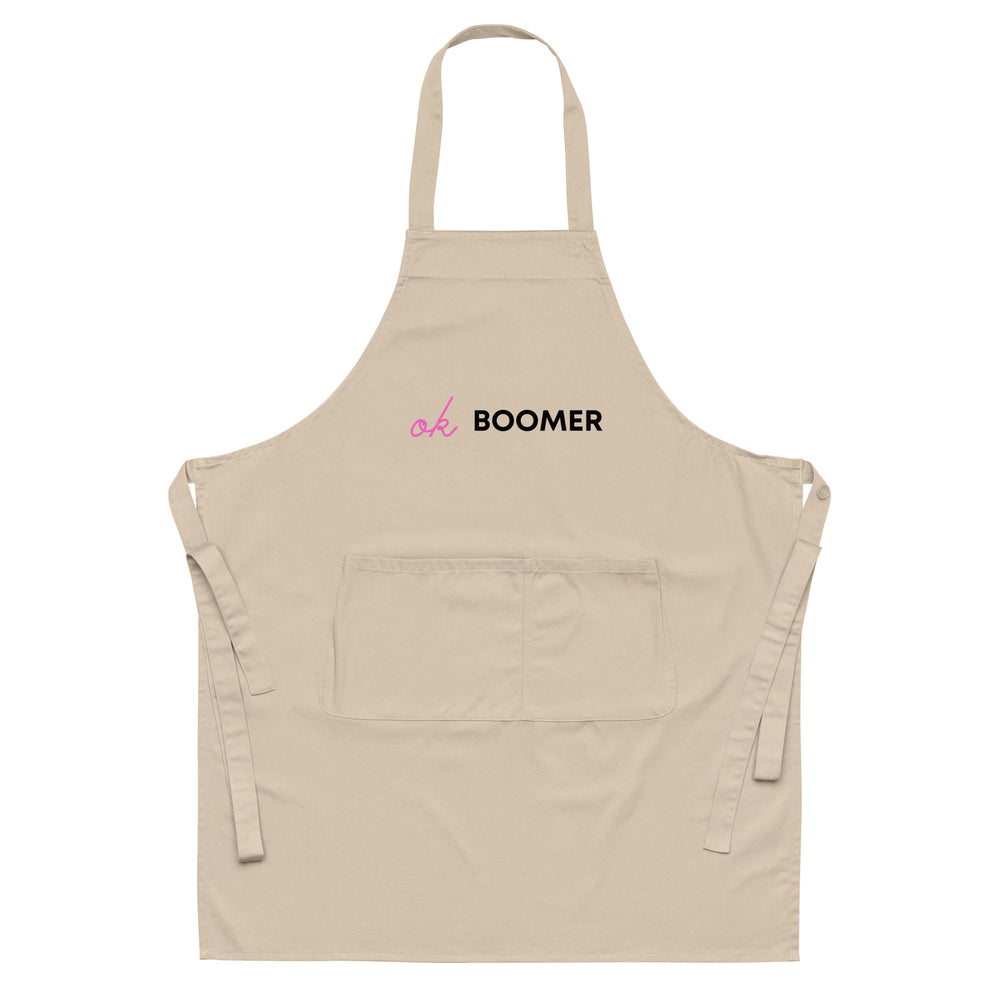 Front view of a beige apron with pink and black “ok BOOMER” text and a large pocket