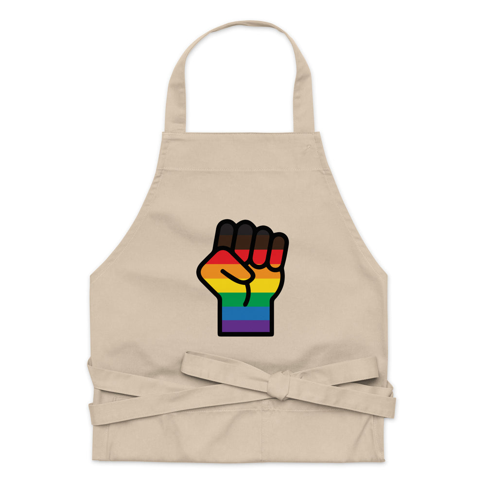 Front view of a beige apron with a rainbow-striped raised-fist graphic and waist ties