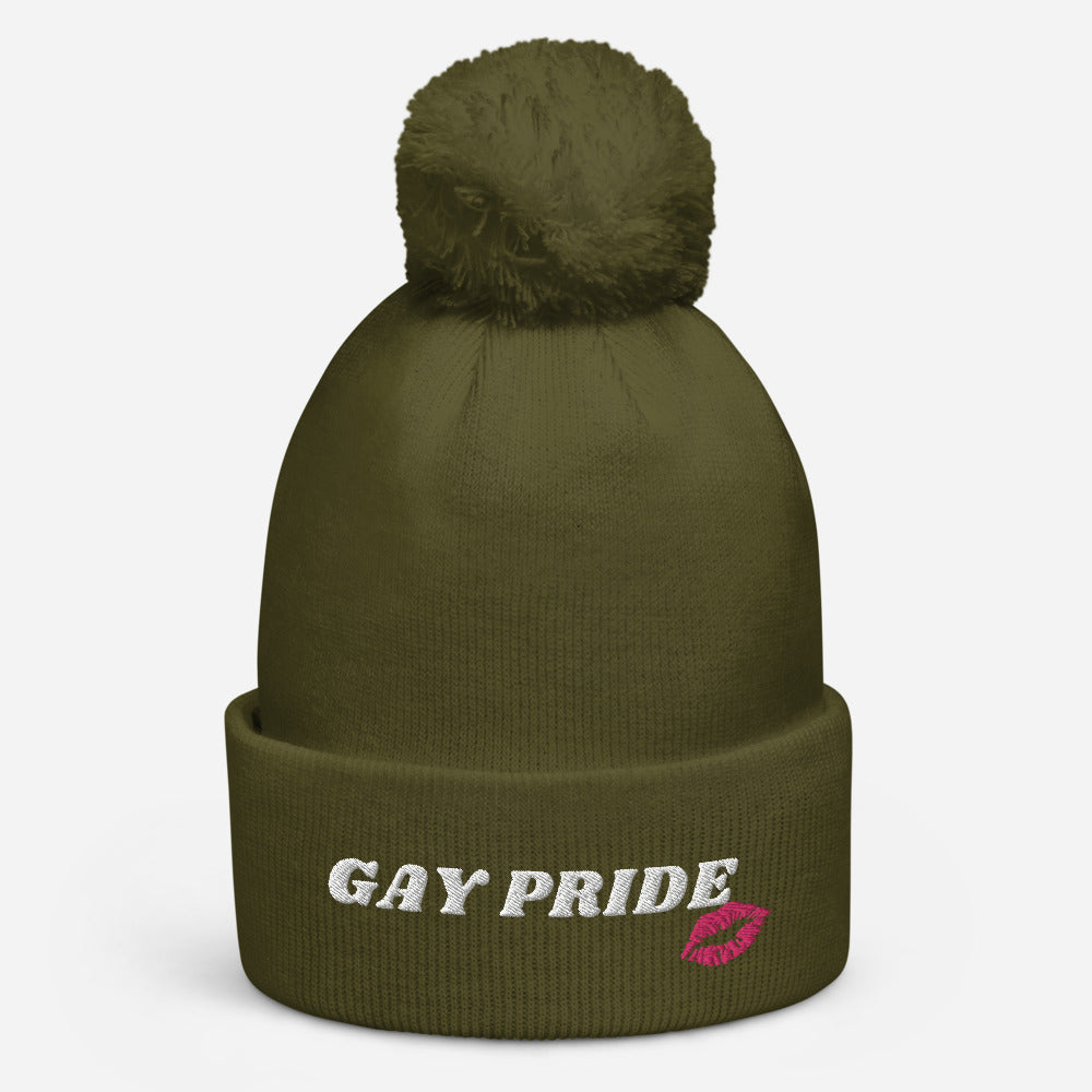 Olive knit pom-pom beanie with white “GAY PRIDE” lettering and a pink lips patch