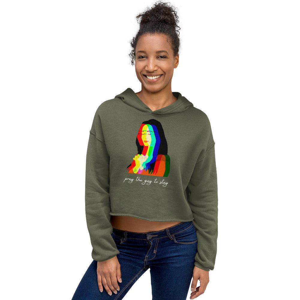 Model wearing an olive cropped hoodie with a rainbow portrait and “pray the gay to stay” text