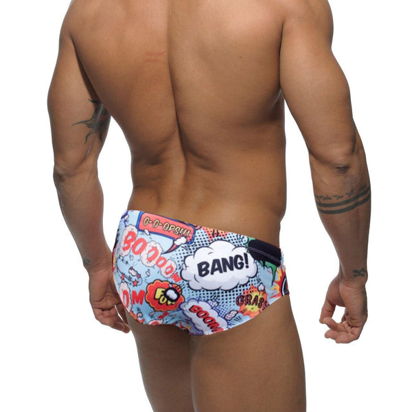 Rear view of a model wearing colorful comic-print swim briefs with “BANG!” and “BOOM” graphics