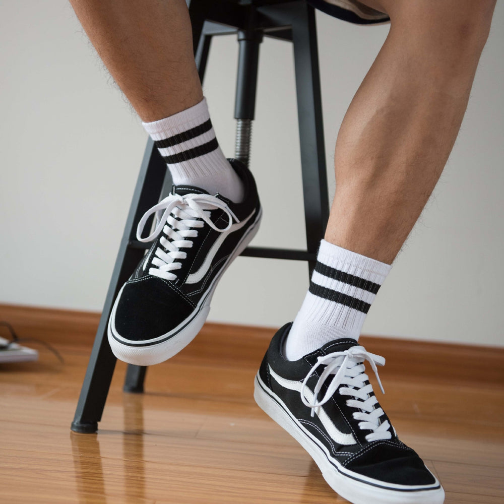 White vintage short sports socks with black stripes worn with black-and-white sneakers