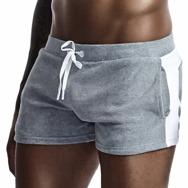 Close-up front view of a model wearing gray velour shorts with white side panels