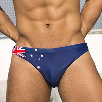 Front view of a model wearing navy swim briefs with an Australian flag design