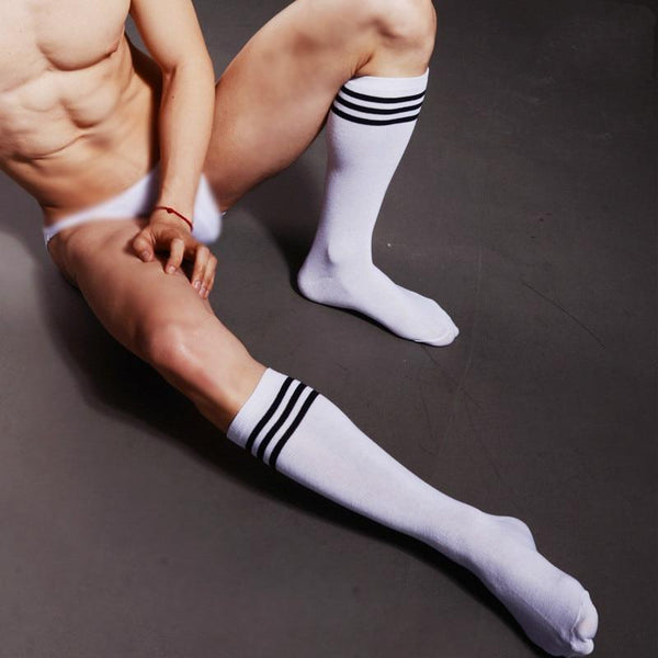 Model wearing white crew sports socks with three black athletic stripes