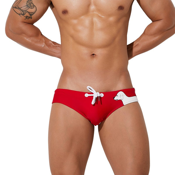 Red low-rise swim briefs with white drawstring and cartoon dog print, modeled from the front
