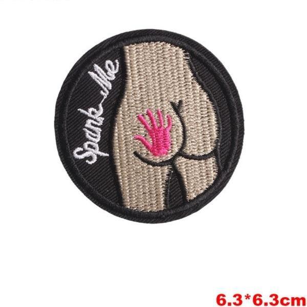 Embroidered iron-on patch showing a pink hand smacking a stylized butt with “Spank Me” text