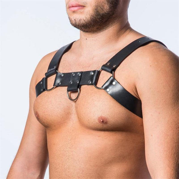 Close-up of a person wearing a black leather-look chest harness with adjustable straps and O-rings