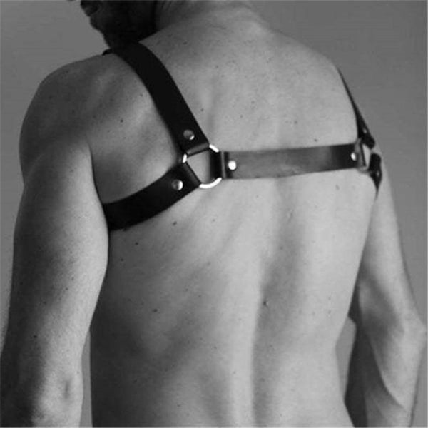 Rear view of a black leather chest harness with shoulder straps, rivets, and metal O-ring hardware
