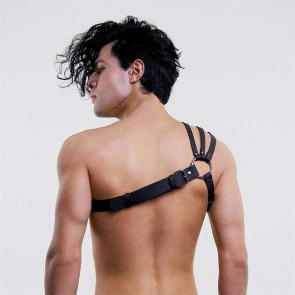 Rear view of a model wearing a black multi-strap harness with buckle and O-ring hardware