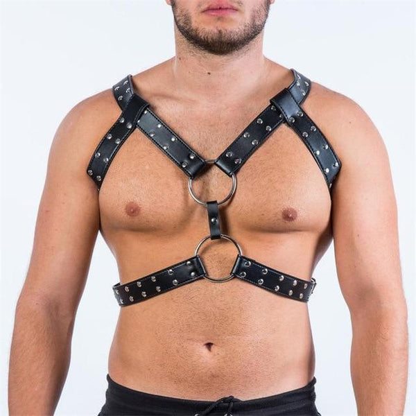 Black leather chest harness with silver studs and large O-rings, worn by a model