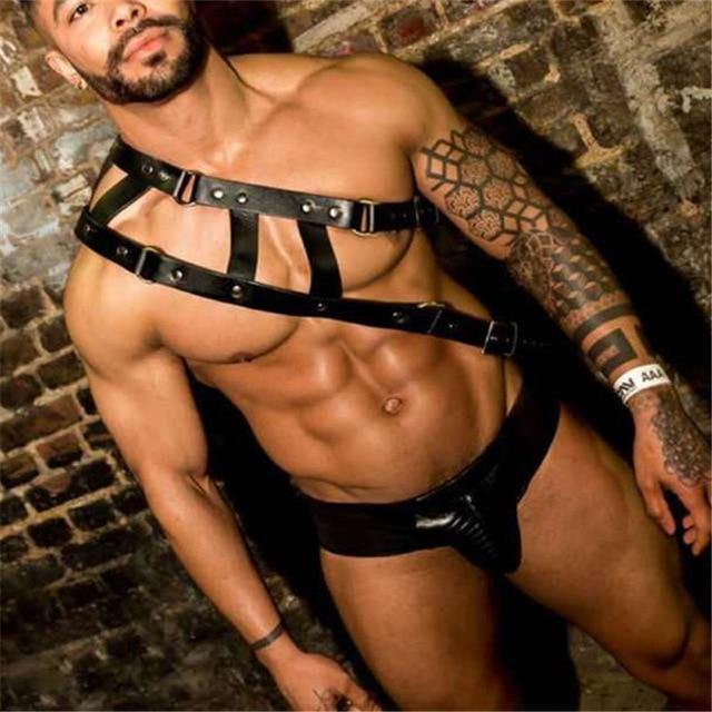 Model wearing a black leather chest harness with studded straps and matching briefs