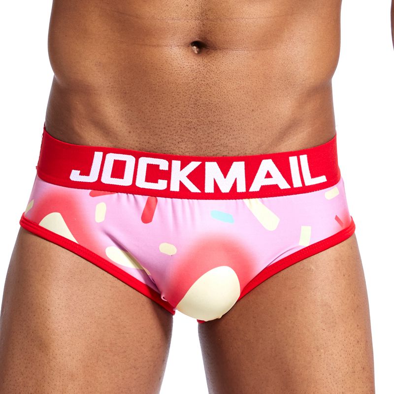 Pink brief-style underwear with a red JOCKMAIL waistband and abstract cream, blue, and red print