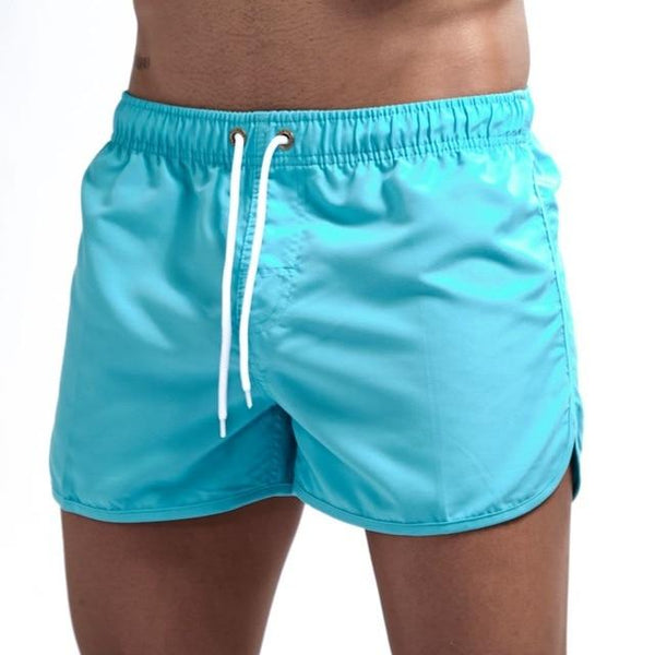 Turquoise swim shorts with an elastic waistband, white drawstring, and side pockets