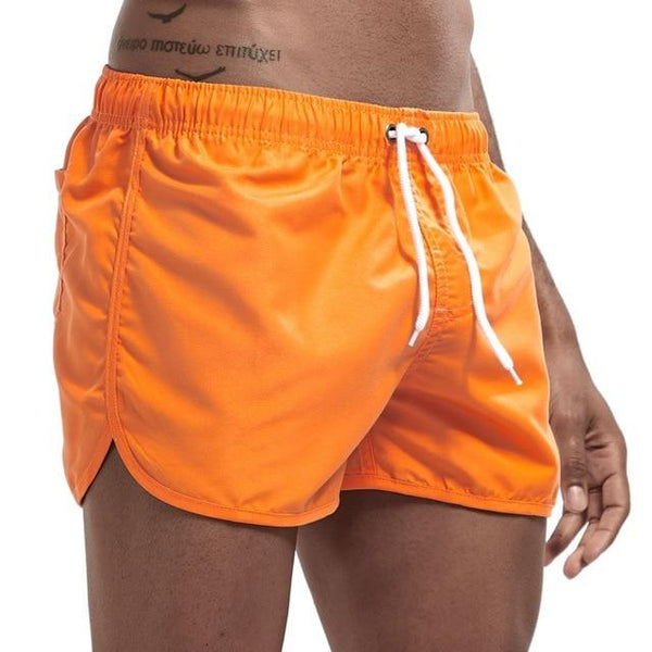 Close-up of a model wearing bright orange swim shorts with white drawstring