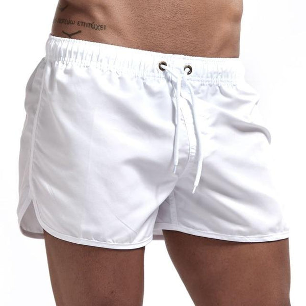 White swim shorts with elastic waistband, drawstring, and side vents on a model