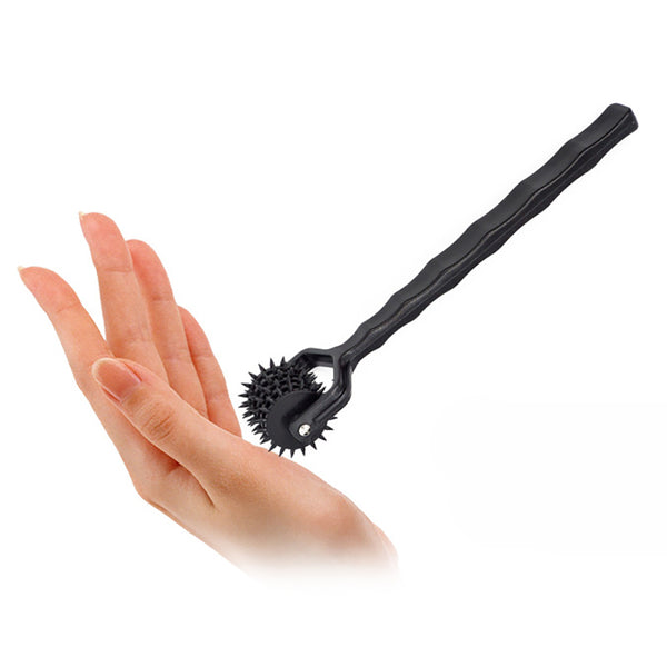 Black spiked Wartenberg wheel resting on an open hand, shown at an angle