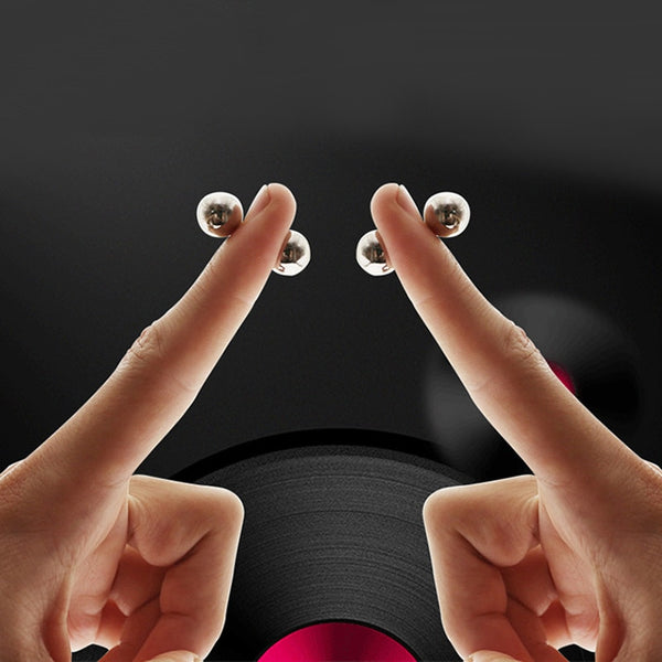 Two hands hold matching silver magnetic nipple balls against a black background