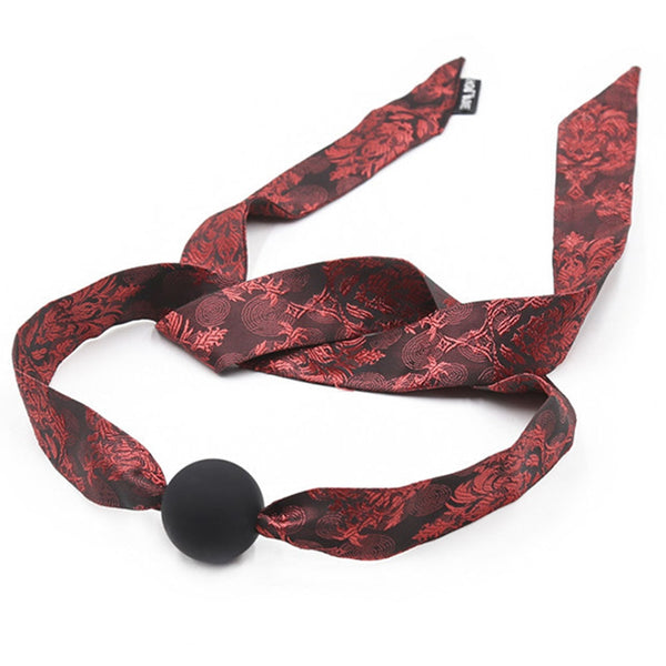 Black ball gag with long red-and-black patterned satin straps, shown coiled on white