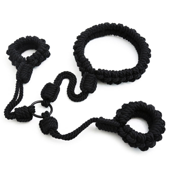 Black braided rope shibari handcuffs arranged on a white background