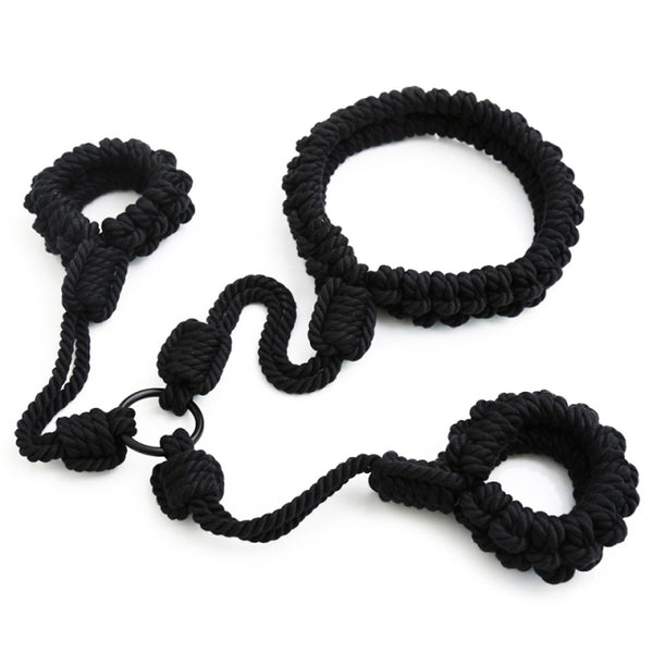 Black braided rope shibari handcuffs arranged on a white background