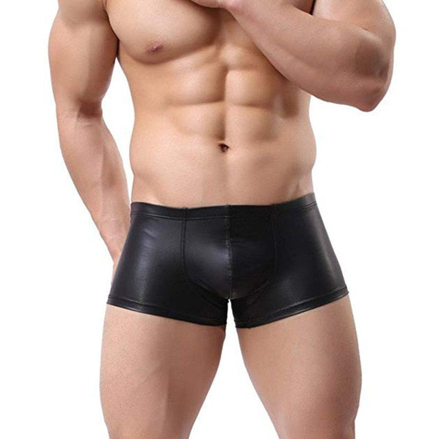 Cropped model wearing glossy black leather-look boxer shorts, front view