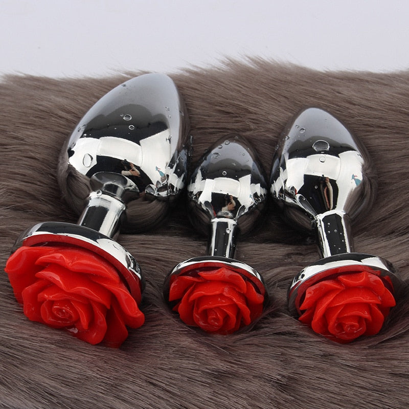 Three reflective stainless steel rose butt plugs arranged on brown faux fur