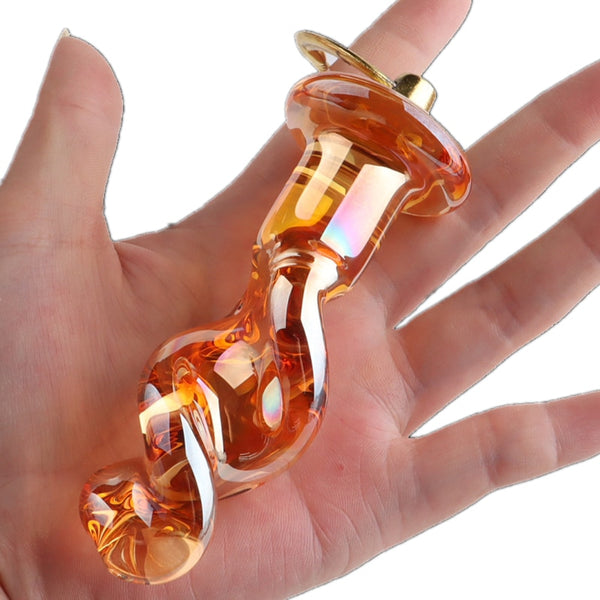 Orange glass butt plug with a flared base resting across an open palm