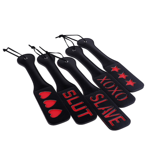 Five black impact-play paddles arranged on white, with red hearts, stars, and cutout lettering