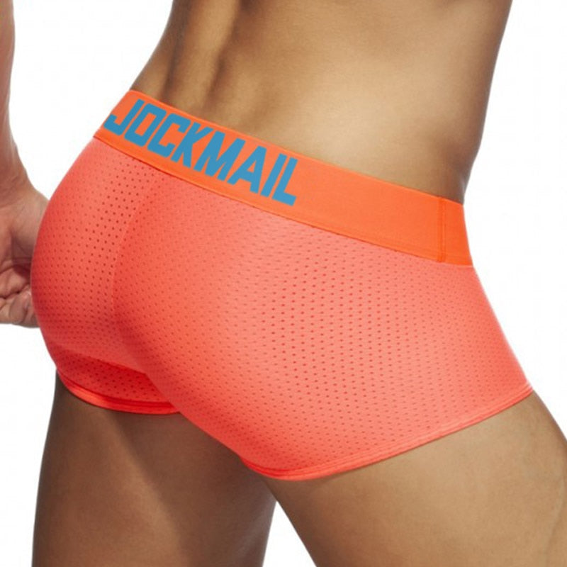 Close-up rear three-quarter view of neon coral mesh boxers with a blue JOCKMAIL waistband