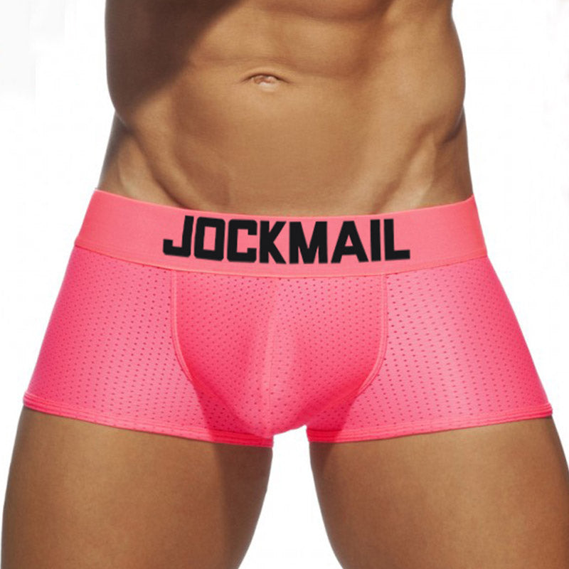 Front view of a model wearing bright pink mesh Jockmail boxer briefs