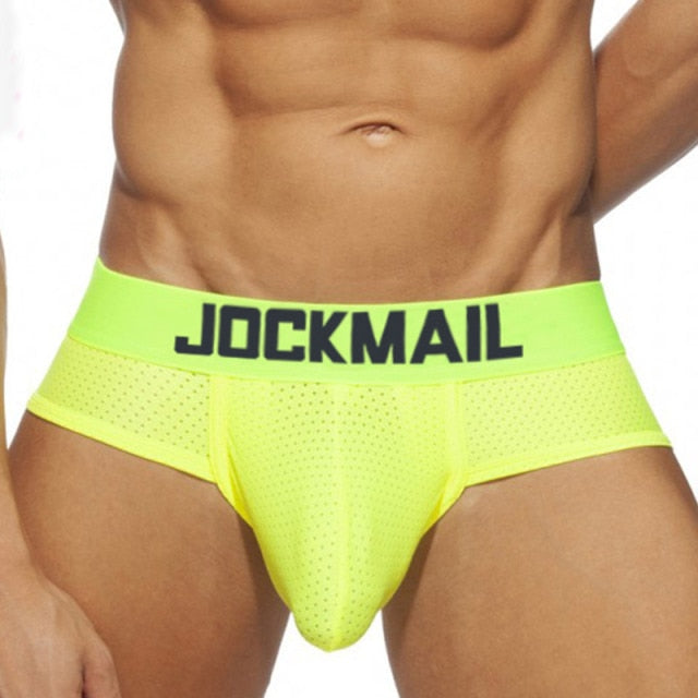 Front view of a model wearing neon yellow mesh briefs with a JOCKMAIL waistband