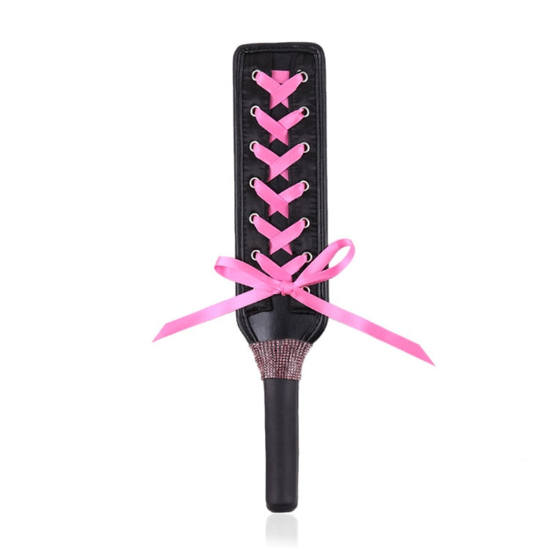 Black lace-up BDSM paddle with a pink ribbon bow and textured handle