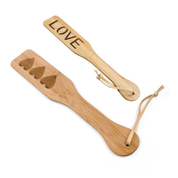Two wooden spanking paddles with heart cutouts and “LOVE” lettering