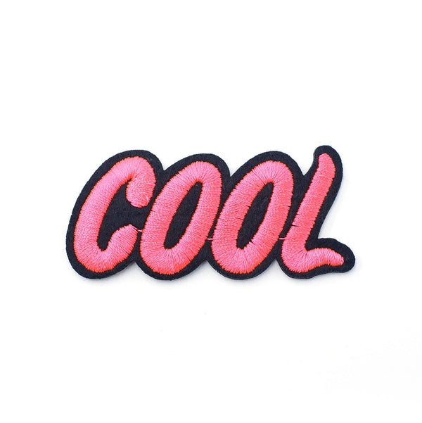Close-up of a pink embroidered “cool” iron-on patch with black edging