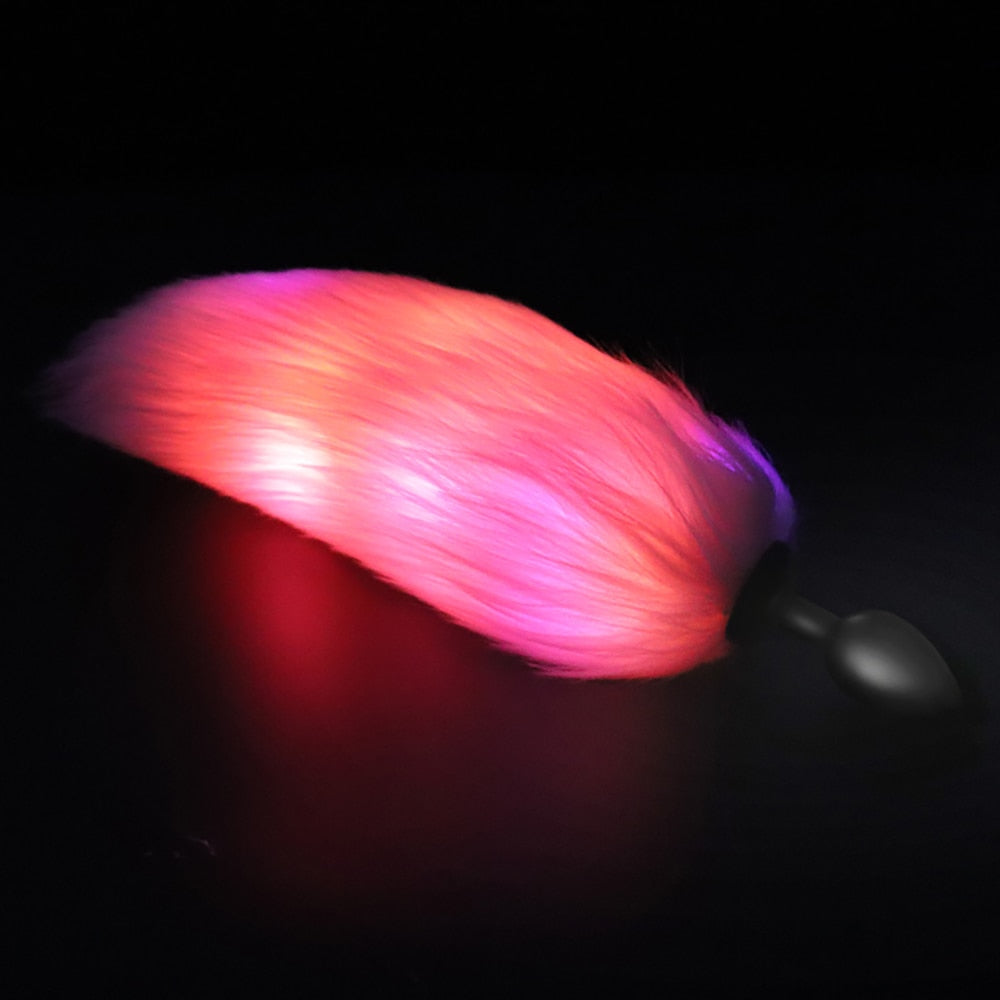 Furry butt plug glowing pink and purple against a black background