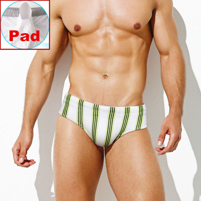Front-facing model wearing white swim briefs with vertical lime and black stripes