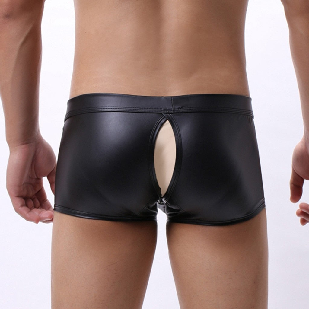 Front view of a model wearing black faux-leather boxer briefs with an oval fly opening