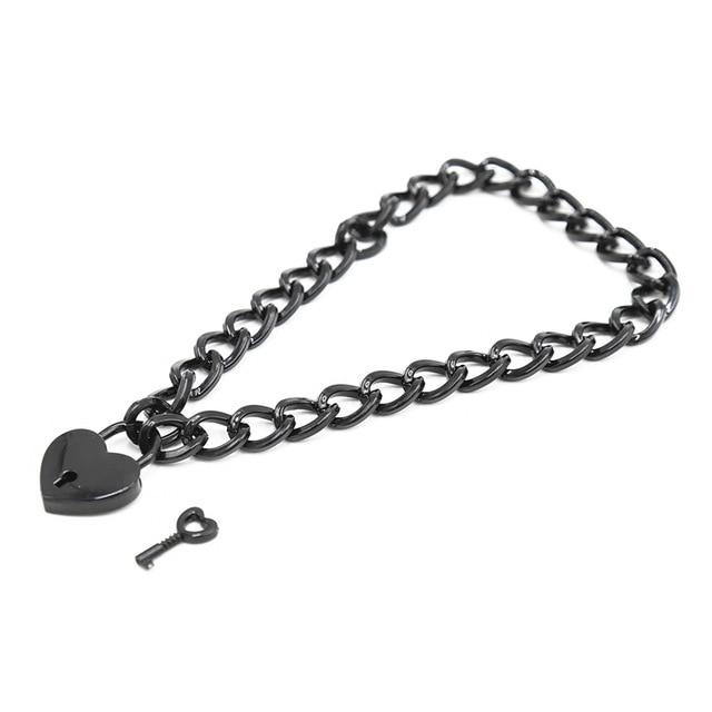 Close-up of a black chain collar with a heart-shaped padlock and separate key