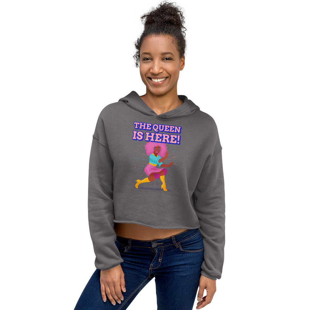 Model wearing a cropped gray hoodie reading “THE QUEEN IS HERE!” with a colorful dancer graphic