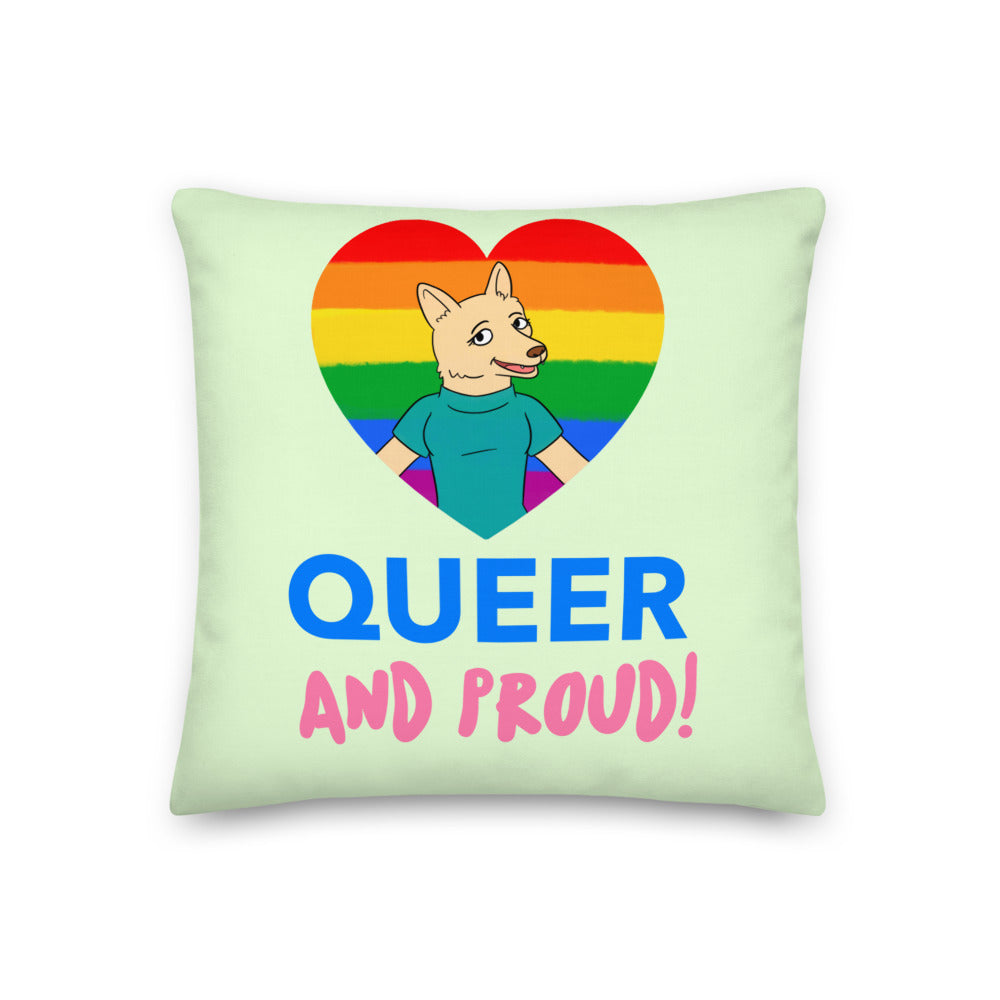 Light green pillow with a cartoon canine in a rainbow heart and “QUEER AND PROUD!” text