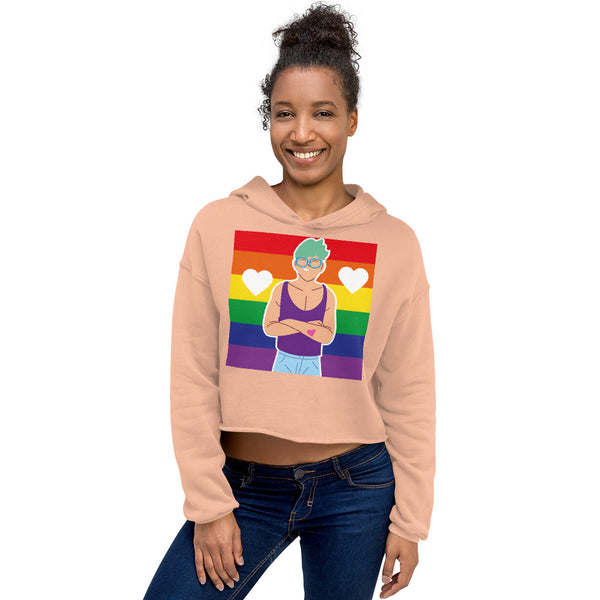 Front view of a model wearing a peach cropped hoodie with a rainbow heart graphic